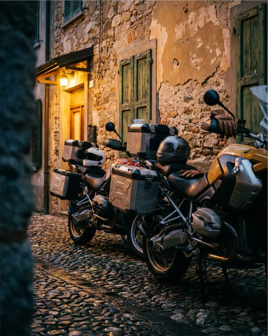 Motorräder auf Kopfsteinpflaster vor einer norditalienischen Trattoria im Abendlicht