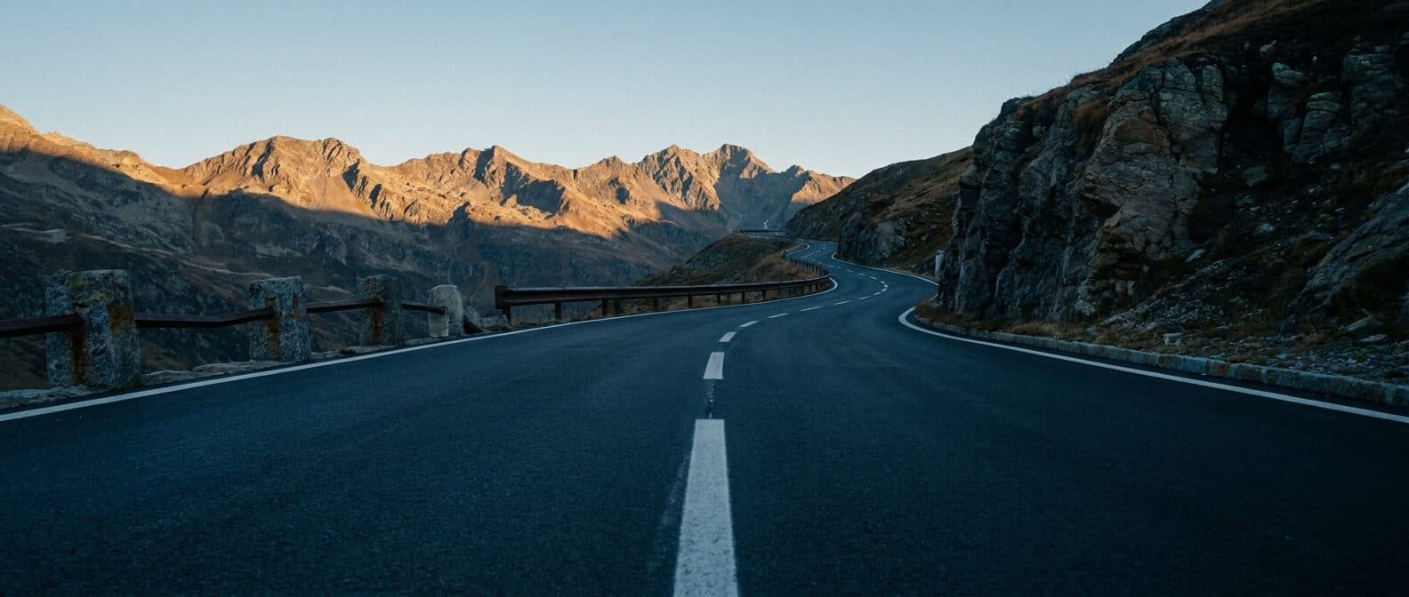Leere Alpenpassstrasse im ersten Morgenlicht