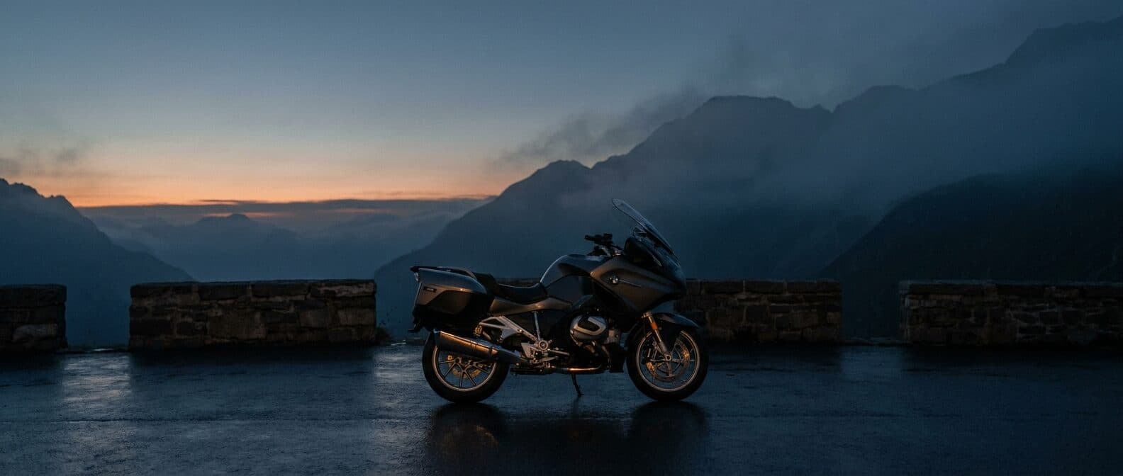 Einzelnes Tourenmotorrad allein auf einem leeren Alpenpass zur blauen Stunde